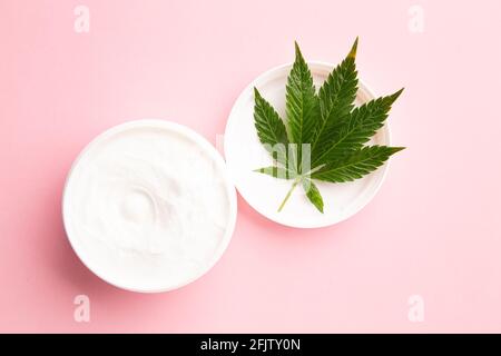 médecine médicinale cbd perfusé lotion topique pour soulager la douleur et l'inflammation sur fond rose, plante de cannabis sur lotion Banque D'Images