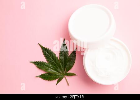 médecine médicinale cbd perfusé lotion topique pour soulager la douleur et l'inflammation sur fond rose, plante de cannabis sur lotion Banque D'Images