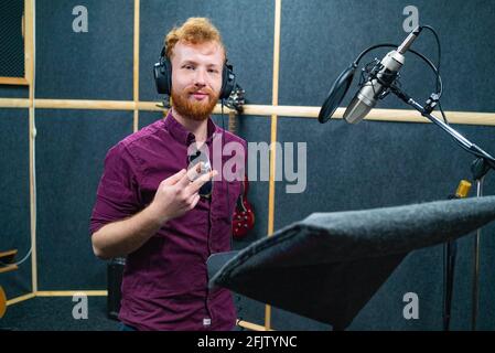 Le jeune barbu reste près du microphone, enregistrant la voix dans un studio professionnel Banque D'Images