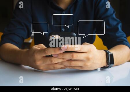 homme tenant main de sms à l'aide de mobile détendez-vous à la maison. image maquette cadre de texte vide pour le message. mise au point douce et sur la lumière dans l'arrière-plan Banque D'Images