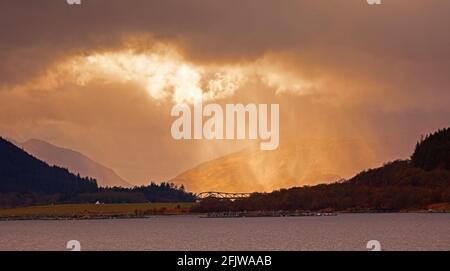 Ballachulish, Lochaber, Écosse, météo britannique. 26 avril 2021. Ciel nuageux spectaculaire avec rayons du soleil traversant entre de fortes averses de pluie au-dessus du pont de la route de Ballachulish. Banque D'Images