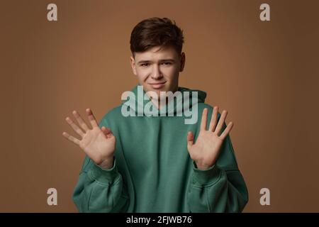 jeune homme effrayé en sweat-shirt sur fond marron. Banque D'Images