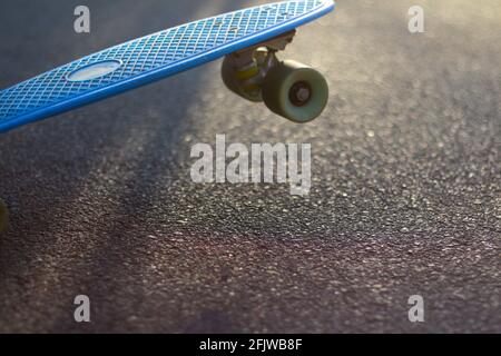 Flou artistique en gros plan sur le panneau bleu penny sur la route asphaltée en plein soleil. Bokeh flou. Mini-croiseur. Concept sport. Planche à roulettes en mouvement. Sur Banque D'Images