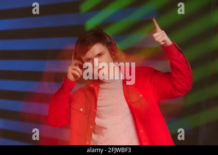 jeune homme en chemise rouge avec casque à l'écoute de la musique Banque D'Images