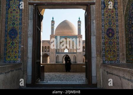 Aperçu dans une mosquée adjacente au Grand Bazar de Kashan avec une femme en tchador noir. Iran. Banque D'Images