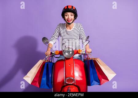 Portrait photo de la bonne fille conduite de vélo après le shopping portant paquets vendredi noir isolé sur fond violet vif Banque D'Images