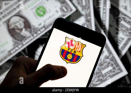 Dans cette photo, l'équipe de football professionnelle espagnole le logo du Futbol Club Barcelona vu affiché sur un smartphone avec une devise USD (dollar des Etats-Unis) en arrière-plan. Banque D'Images