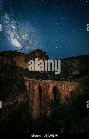 Paysage de ciel étoilé. L'ancien aqueduc romain connu sous le nom de 'Peña Cortada' et la voie lactée vue en été dans l'hémisphère Nord. Valence, Espagne Banque D'Images