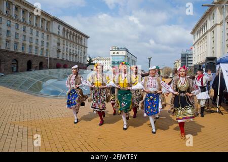 Sofia, Bulgarie - avril 20 2021 : des hommes et des femmes vêtés de vêtements traditionnels dansent devant l'Assemblée nationale et le Conseil des ministres Banque D'Images