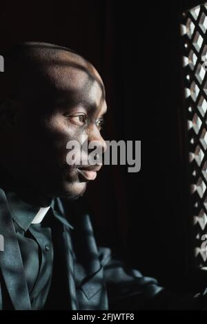 Homme africain assis à la confession et à l'écoute de la confession dedans l'église Banque D'Images