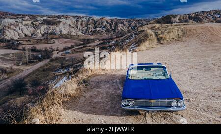 Cappadoce, Turquie. Voiture rétro bleue américaine dans le désert pendant le coucher du soleil. Photo de haute qualité Banque D'Images