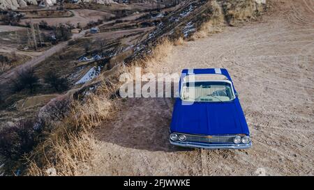 Cappadoce, Turquie. Voiture rétro bleue américaine dans le désert pendant le coucher du soleil. Photo de haute qualité Banque D'Images