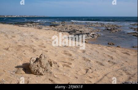 Une plage vide avec du sable et des pierres en face de la mer et un ciel bleu Banque D'Images