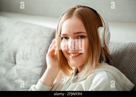 Bonne jeune femme assise sur un canapé avec écouteurs. Femme ou jeune fille se reposant, Bliss profiter d'écouter de la musique sur le canapé à l'intérieur de la maison de la vie Banque D'Images