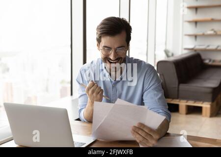 Un homme excité a lu les bonnes nouvelles dans le document papier postal Banque D'Images