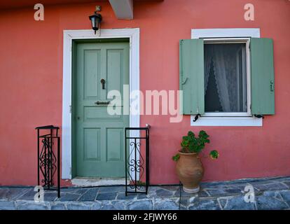 Façade de maison néoclassique avec un mur en stuc rouge vénitien, porte et volets en bois vert Vermont et lanterne murale en fonte à Nafplio, Grèce. Banque D'Images