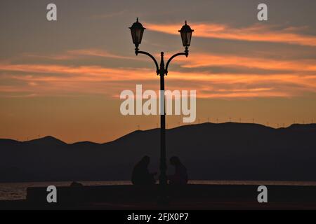 Coucher de soleil paysage avec une silhouette de lumière de rue et les montagnes sur le fond au Vieux Port de Nauplie à Argolis Péloponnèse, Grèce. Banque D'Images