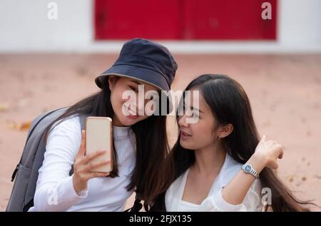 Les femmes asiatiques, tenant la recherche sur les smartphones. Faisant le selfie avec des amis et souriant. Banque D'Images