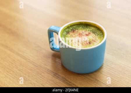 Tasse bleue avec thé vert matcha latte, avec fraises lyophilisées sur une table en bois, espace de copie. Concept de nutrition saine, boissons avec légumes o Banque D'Images
