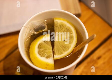 Thé avec des tranches de citron dans un verre en plastique de près Banque D'Images