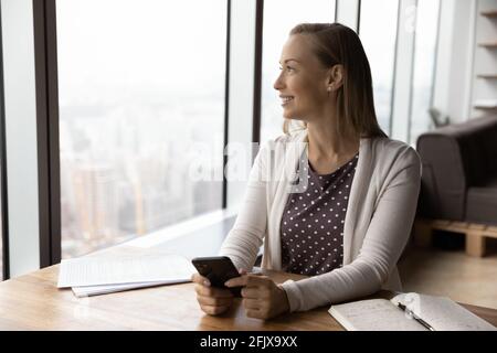 Une femme heureuse utilise le rêve de téléphone portable d'opportunités Banque D'Images