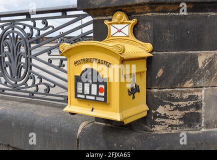 Une boîte postale jaune décorative classique attachée à la balustrade historique en grès de la vieille ville pittoresque de Dresde. Banque D'Images
