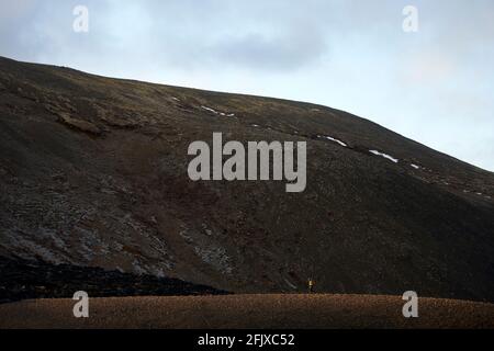 Alpiniste distant debout sur le sommet de montagne rugueux dans les montagnes Banque D'Images