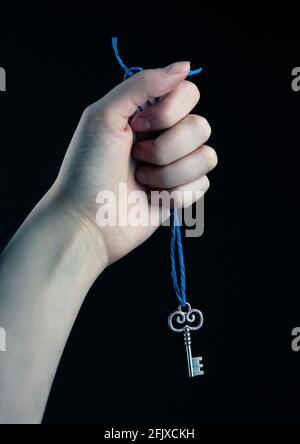 Main tenant une ficelle bleue avec une clé argentée Banque D'Images