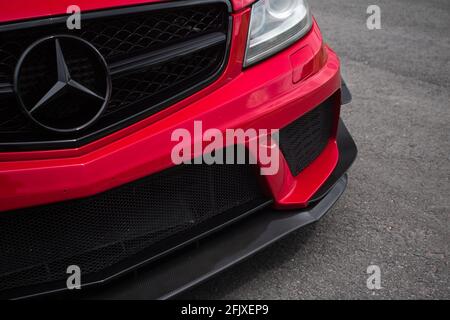 Le coin de bouclier avant d'UN 2012 Fire Opal Rouge Mercedes Benz C63 AMG Black série W204 avec carbone Canards à fibres optiques Banque D'Images