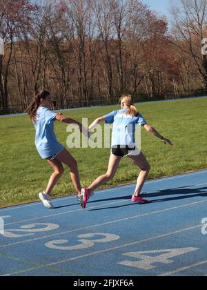 Les jeunes filles qui participent à une piste d'école intermédiaire se rencontrent dans le comté de Sussex, dans le New Jersey. Ils passent le bâton et le sprint. Banque D'Images