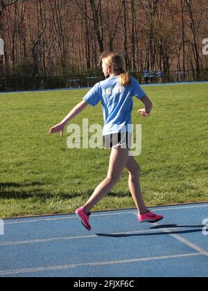 Les jeunes filles qui participent à une piste d'école intermédiaire se rencontrent dans le comté de Sussex, dans le New Jersey. Ils passent le bâton et le sprint. Banque D'Images