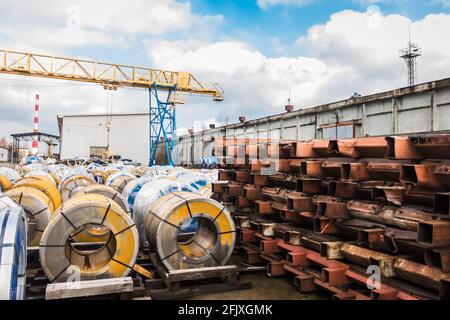 Stockage de vieux matériaux métalliques rouillés dans une zone industrielle ouverte à proximité d'un entrepôt et d'une grue de pont. Banque D'Images