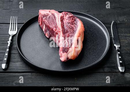 Italian Florentine T bone DRY Aged beef Meat Steak Set, sur plaque, sur fond de table en bois noir Banque D'Images