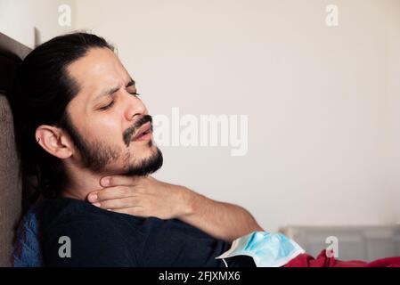 Jeune latino malade au lit à la maison avec la gorge la douleur Banque D'Images