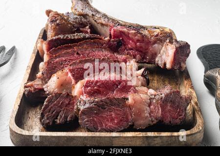 Barbecue traditionnel, set de tranches de steak de tomahawk de Wagyu vieilli sec, sur un plateau de service en bois, sur fond de pierre blanche Banque D'Images