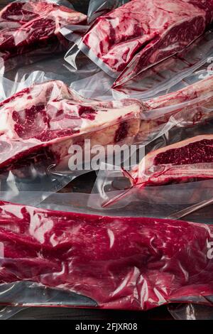 Steaks de bœuf frais et savoureux avec os enveloppés dans un emballage en plastique sous vide au marché, tomahawk, t-bone, steak de club, entrecôtes d'yeux et de filets, on o Banque D'Images