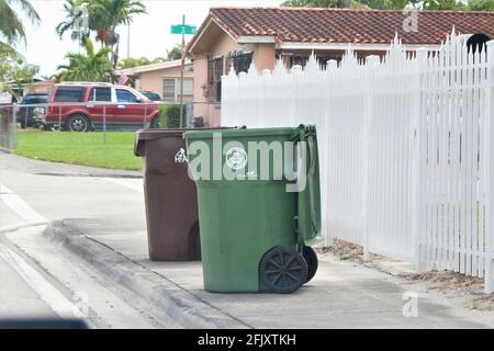 Recyclez et poubelles de la ville de Hialeah on un trottoir devant une maison résidentielle Banque D'Images