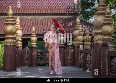 Belle fille dans la robe nationale thaïlandaise lumineuse avec maquillage oriental, Voyage en Thaïlande Banque D'Images
