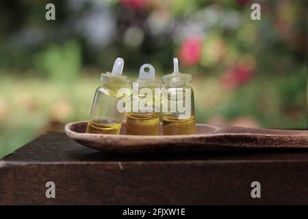 Bouteilles d'huile d'olive dans de minuscules bouteilles de teinture qui se trouvent dans un champ d'herbe sur une cuillère en bois, pour cuisiner avec un espace de copie Banque D'Images