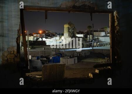 Mossoul, Irak. 26 avril 2021. Une vue de l'intérieur de la fenêtre d'une maison détruite montre le minaret Al-Hadba détruit la nuit. La mosquée Al-Nuri a été construite en 1172 et qui comprend également le minaret Al-Hadba, est actuellement en cours de reconstruction dans son ancienne conception par l'UNESCO après qu'elle ait été détruite pendant la guerre contre l'EI (État islamique d'Irak et de Syrie). Crédit : SOPA Images Limited/Alamy Live News Banque D'Images