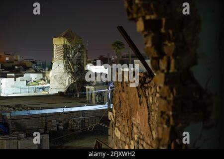 Mossoul, Irak. 26 avril 2021. Une vue de l'intérieur de la fenêtre d'une maison détruite montre le minaret Al-Hadba détruit la nuit. La mosquée Al-Nuri a été construite en 1172 et qui comprend également le minaret Al-Hadba, est actuellement en cours de reconstruction dans son ancienne conception par l'UNESCO après qu'elle ait été détruite pendant la guerre contre l'EI (État islamique d'Irak et de Syrie). Crédit : SOPA Images Limited/Alamy Live News Banque D'Images