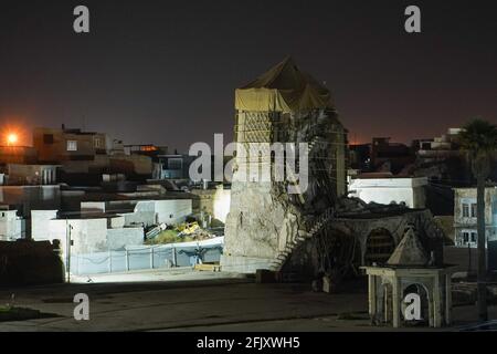 Mossoul, Irak. 26 avril 2021. Une vue depuis le toit d'une maison détruite montre le minaret Al-Hadba détruit la nuit. La mosquée Al-Nuri a été construite en 1172 et qui comprend également le minaret Al-Hadba, est actuellement en cours de reconstruction dans son ancienne conception par l'UNESCO après qu'elle ait été détruite pendant la guerre contre l'EI (État islamique d'Irak et de Syrie). Crédit : SOPA Images Limited/Alamy Live News Banque D'Images