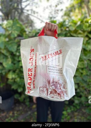 Une personne tenant un sac d'achats réutilisable de joe commerçant qui est écologique dans un cadre extérieur. Banque D'Images