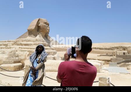 Giza, Égypte. 26 avril 2021. Un touriste pose pour une photo avec le Sphinx à l'endroit pittoresque des Pyramides de Gizeh, en Égypte, le 26 avril 2021. Le tourisme local a été sévèrement touché par la COVID-19, avec moins de touristes vus dans la région pittoresque maintenant. Crédit: Wang Dongzhen/Xinhua/Alay Live News Banque D'Images