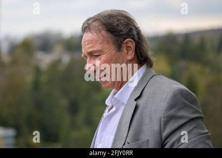 Un homme d'affaires d'âge moyen réfléchi regardant le sol avec un expression contemplative dans un portrait de profil à l'extérieur contre un rural toile de fond Banque D'Images