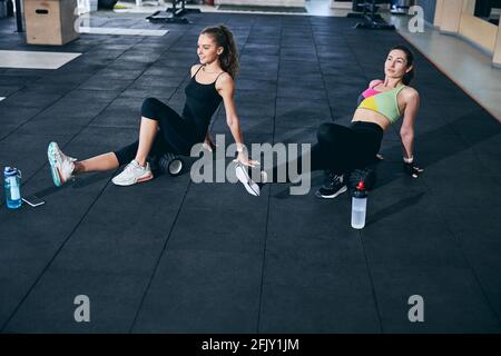 Deux athlètes féminins s'exerçant sur le sol à l'aide de rouleaux en mousse Banque D'Images