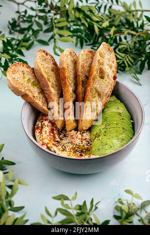 Bol de houmous avec tranches d'avocat et de toasts Banque D'Images