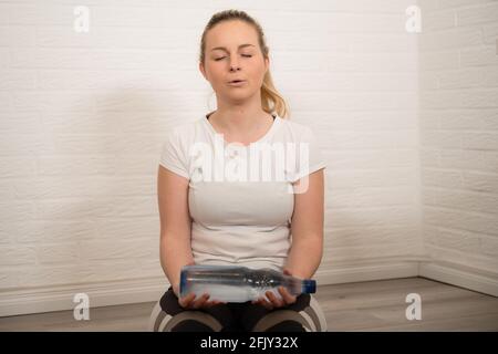 Bonne femme blonde faisant de l'exercice de forme physique avec des bouteilles d'eau - entraînement sportif de base comme entraînement à la maison Banque D'Images