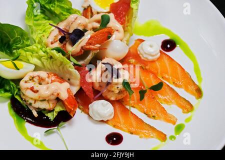 cocktail de crevettes et salade gravlax de saumon mariné avec petit bijou laitue et herbes dans une assiette blanche Banque D'Images