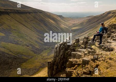 Une randonneur solitaire donne sur High Cup Nick, une vallée classique en forme de U dans la région des Pennines du Nord en Angleterre. Banque D'Images